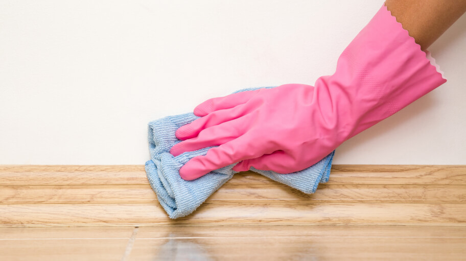 A cleaner with gloves cleaning skirting boards
