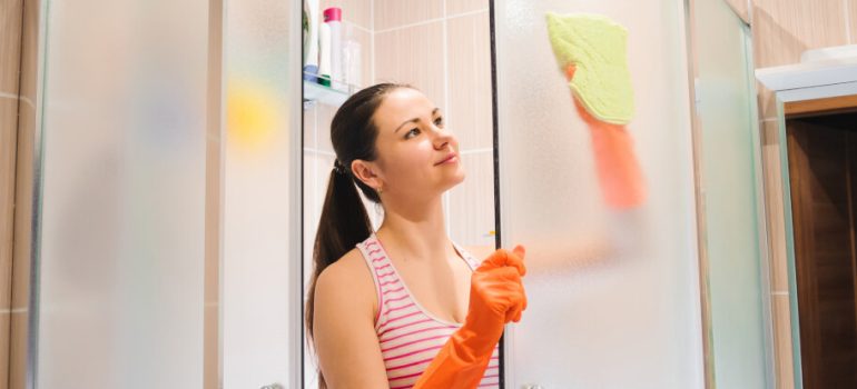 A woman cleaning shower glass door with ease.