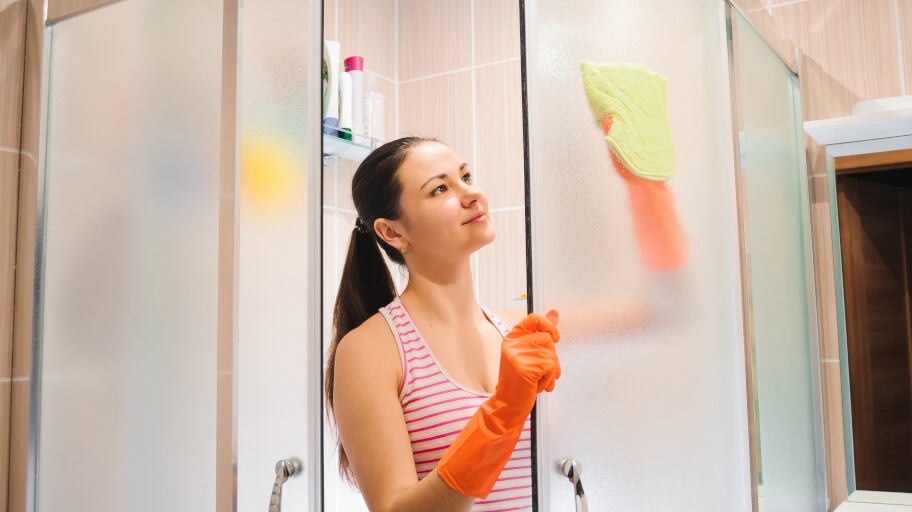 A woman cleaning shower glass door with ease.