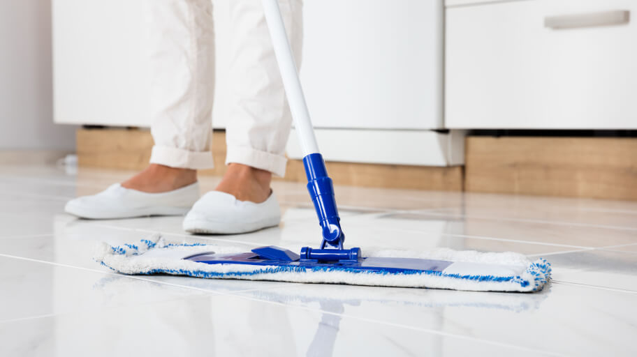 Cleaning a white tiled floor with a mop