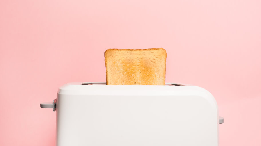 A white toaster with lightly toasted bread on pink backgroud