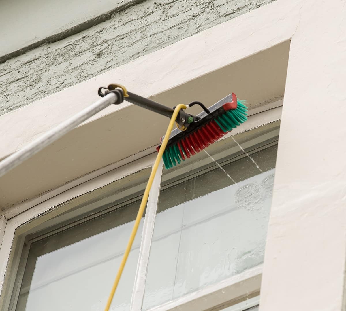 Cleaning second floor window with a special window cleaning machine