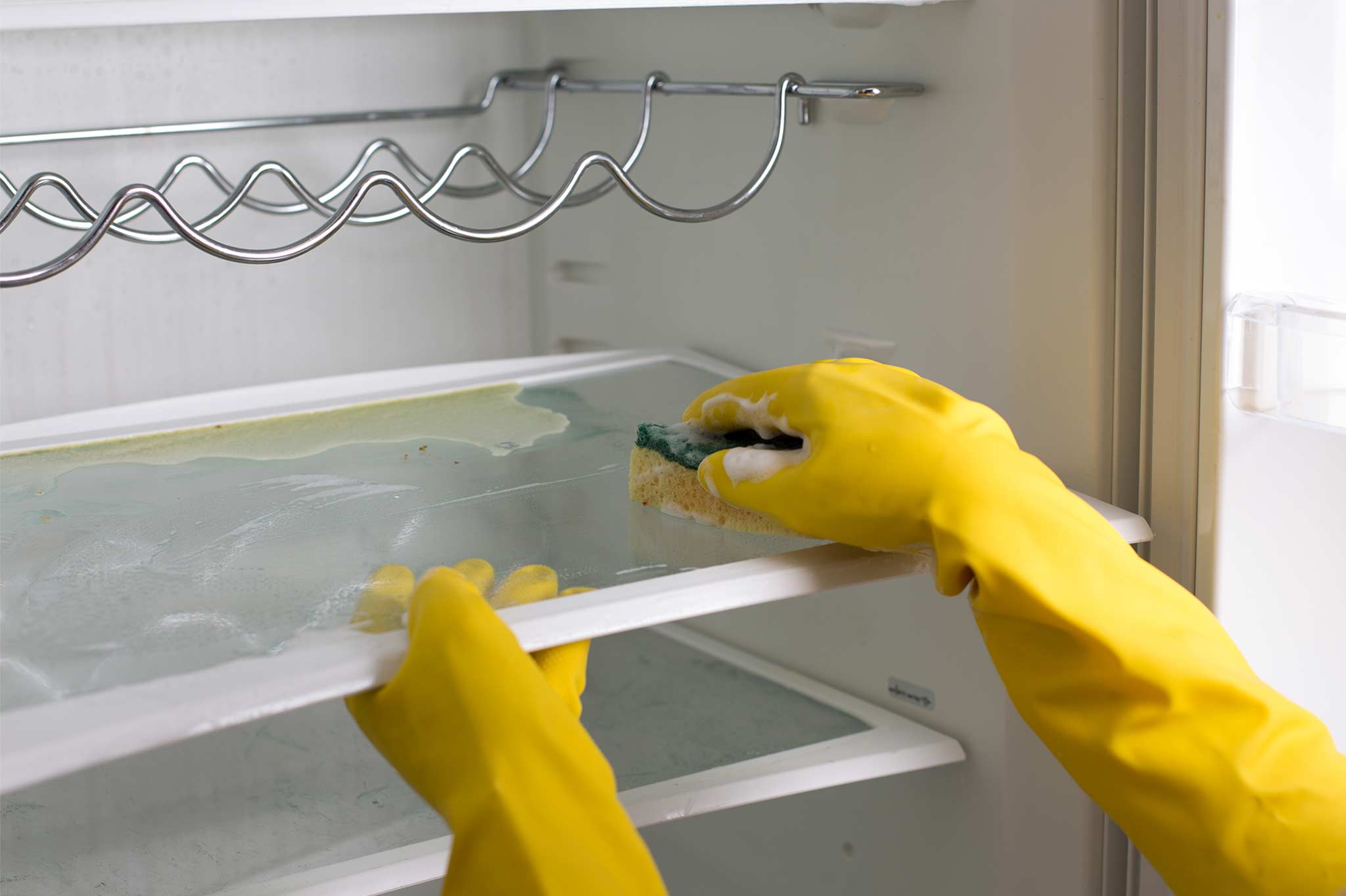 Cleaners hands with gloves cleaning a dirty fridge
